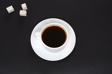 Black coffee and white sugar on a black background.