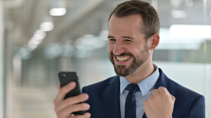 Portrait of Middle Aged Businessman Celebrating Success on Smartphone 