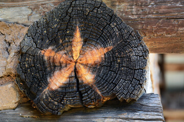 A star appears as part of the natural aging process on a cut log used in a wooden cabin