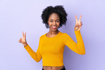 Young African American woman isolated on purple background showing victory sign with both hands