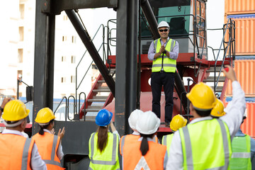 warehouse boss engineer standing on crane car with factory workers clapping hands for congratulations work in containers warehouse storage