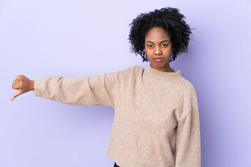 Young African American woman isolated on purple background showing thumb down with negative...