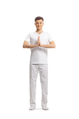 Young man in white clothes standing and practicing yoga