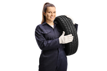 Young female mechanic worker carrying a car tire