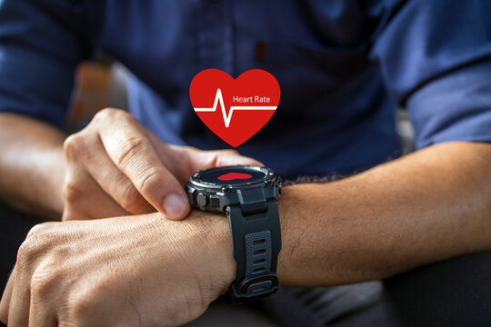 male hand holding wearing smart watch showing heart rate icon with soft-focus and over light in the background.