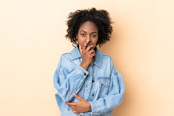 Fototapeta na wymiar Young African American woman isolated on beige background surprised and shocked while looking right