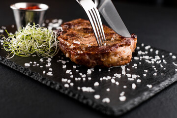 fried chicken breast on the board cut with a knife and fork. next to tomato, bell pepper and lemon with herbs and spices