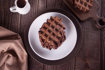Homemade chocolate waffles on the wooden table.