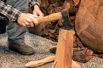 Man uses ax to break wood to use for bbq. Preparation of wood to light a fire to cook food on grill outdoor. Close-up of hands holding a cutting tool. Camping, barbecue, outdoors, recreation, concept