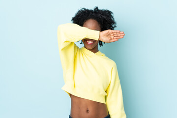 Young African American woman isolated on blue background covering eyes by hands