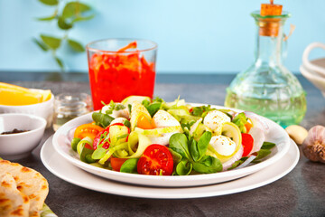salad of fresh cherry tomatoes, mozzarella, basil, radish and other greens on the dinner table