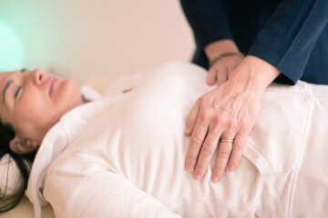 Fototapeta na wymiar Therapist man doing Holistic therapy Reiki to a woman. Energy treatment with the heat of the palm hands. Japanese energy healing. Wellness, health, relax, well-being and alternative medicine concept.