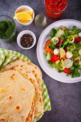 Homemade Indian naan flatbread with fresh salad and dips on the dinner table. Top view.
