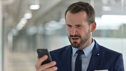 Portrait of Upset Middle Aged Businessman having Loss on Smartphone 