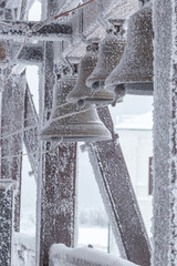 an iron bell covered with frost and snow on a frosty day on the top of Mount Belorie next to the Belogorsk monastery. Ural, Russia.