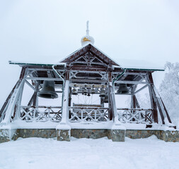 an iron bell covered with frost and snow on a frosty day on the top of Mount Belorie next to the Belogorsk monastery. Ural, Russia.