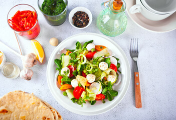 salad of fresh cherry tomatoes, mozzarella, basil and other greens on the dinner table with pita flat bread
