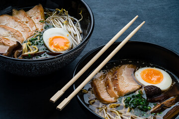 ramen noodle soup with chicken, shiitake mushroms and egg in black bowl
