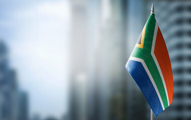 A small flag of South Africa on the background of a blurred background - obrazy, fototapety, plakaty