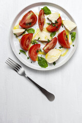 Homemade Italian caprese salad with sliced tomatoes, mozzarella cheese, basil and olive oil