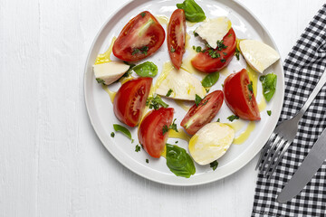 Homemade Italian caprese salad with sliced tomatoes, mozzarella cheese, basil and olive oil