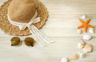Hat, sunglasses and starfish with shells lie on a wooden surface. View from above