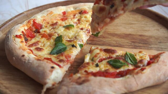 take a piece of classic pizza margherita with mozzarella and basil. cooking pizza neapolitan at home, fresh hot pizza slice