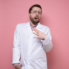 Strange, frightened doctor with glasses on forehead and tongue sticking out stares in shock. Stress at work. Pink background.