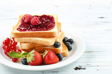 Toasts with jam with fresh berries on white wooden table