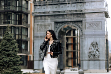 Happy young business woman talking on phone while walking on the street