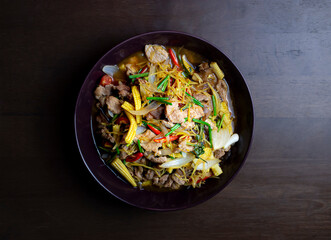 Stir fried pork and ginger with mixed vegetable in a black plate on wooden table
