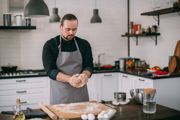 A male chef prepares dough at home in the kitchen