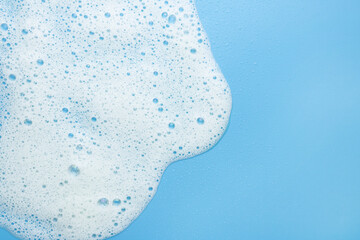 White foam, mousse on a blue background. Border for their foam text. The concept of foaming products, cosmetics or cleaning products. - obrazy, fototapety, plakaty