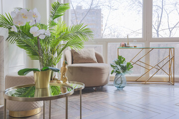 very light and bright interior of luxurious cozy living room with chic soft beige furniture with gold metallic elements, huge window to the floor and wooden parquet