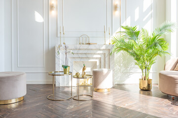 very light and bright interior of luxurious cozy living room with chic soft beige furniture with gold metallic elements, huge window to the floor and wooden parquet