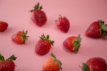 Delicious juicy ripe red strawberries on a pink background. Close-up shot of strawberries on a grater. Berry pattern