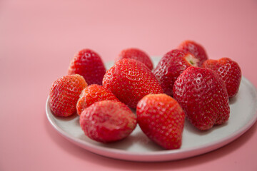 Delicious juicy ripe red strawberries on a pink background. Close-up shot of strawberries on a grater. Macro shot of garden strawberry