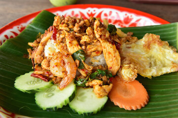 Rice topped with stir-fried pork ,shrimps and basil on banana leaf.