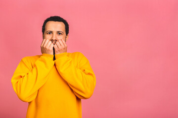 Portrait of young amazed african american black man with afro hairstyle in casual, looking in camera with opened mouth and shocked expression. Isolated over pink background.