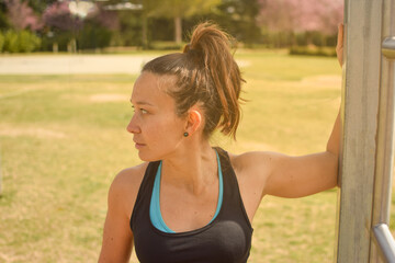 White Caucasian woman with her hair tied up doing stretching exercises in the park. Concept of outdoor exercise, wellness, health.