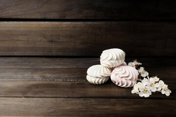 marshmallow. meringue decorated with a white flower on a dark wood background.