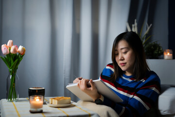 asian woman working from home and relax by read book during stage quarantine