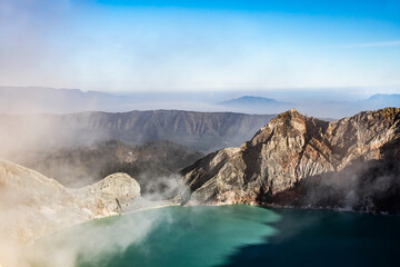 Fototapeta na wymiar Ijen volcano crater with lake and sulphur mining. Beautiful Landscape mountain and green lake with smoke sulfur in the morning in a Kawah Ijen volcano. Beautiful landmark from East Java, Indonesia