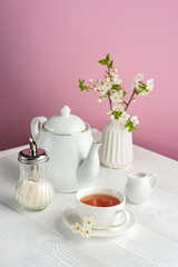 Spring composition with white tea utensils on a pink background.