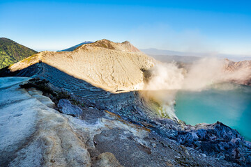 Ijen volcano crater with lake and sulphur mining. Beautiful Landscape mountain and green lake with smoke sulfur in the morning in a Kawah Ijen volcano. Beautiful landmark from East Java, Indonesia