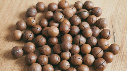 Whole macadamia nuts on the table. Many macadamia nuts lie on the table as a background.