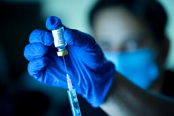 Doctor pulling vaccine liquid from vial to vaccinate man