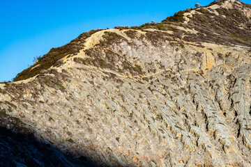 Mountain furrows wave surface pattern from lava flow at the top of Ijen volcano crater.Beautiful Landscape mountain and green lake with smoke sulfur in a Kawah Ijen volcano.East Java, Indonesia