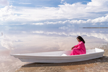 Beautiful stylish pensive relaxed sad mixed race woman in pink suit siting in white boat on shore...