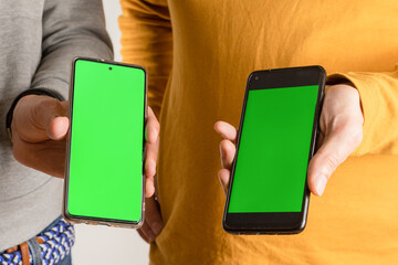 Two people show their smartphones with green screen